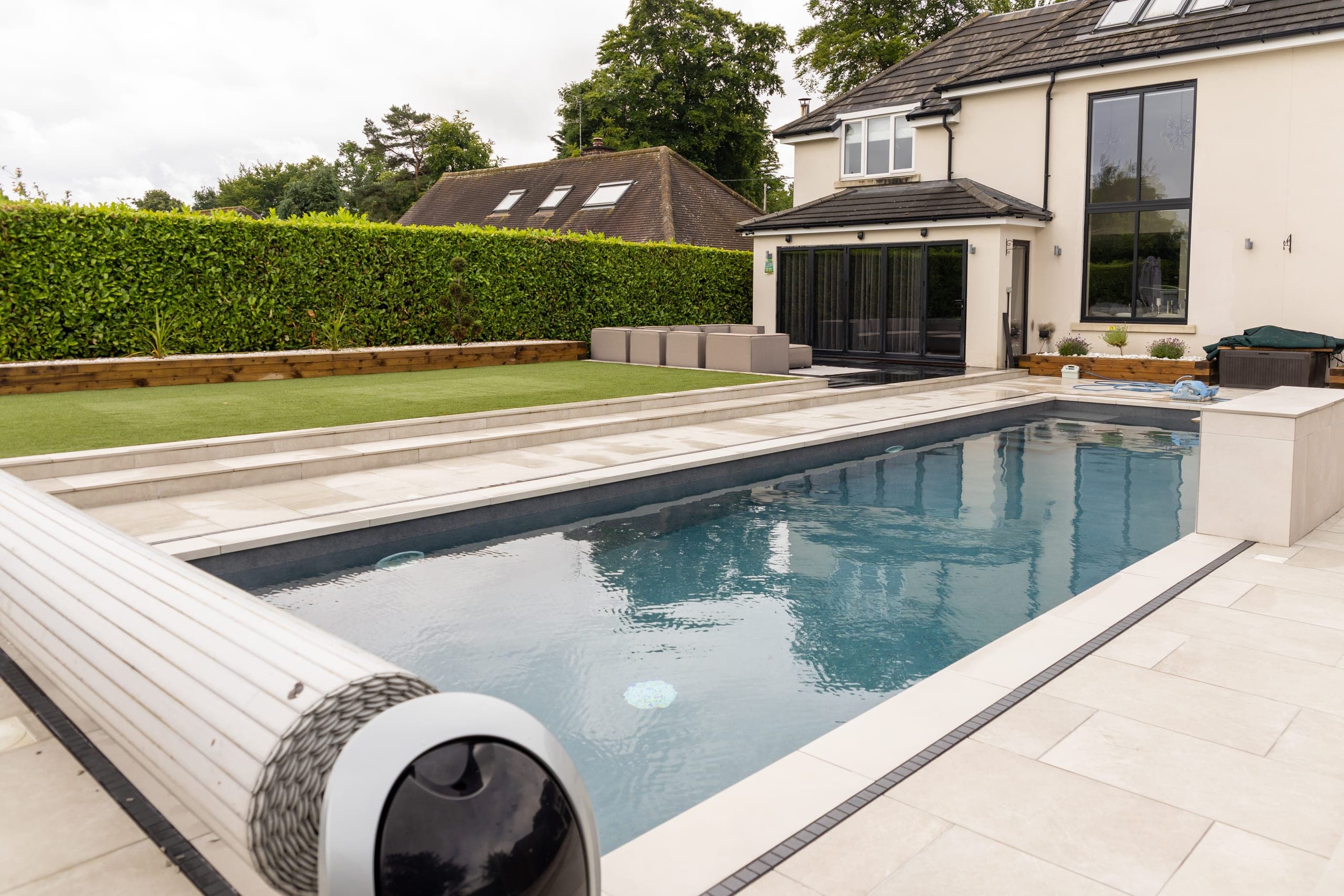 The heated pool with its roller cover, the paved terrace and the back of the house